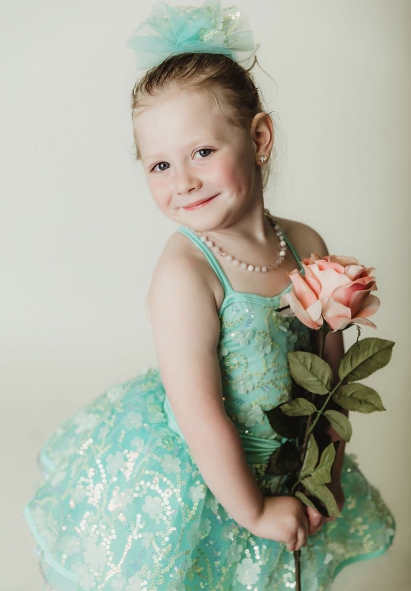 One of our littlest dancers in a mint sequin tutu, holding a pink rose